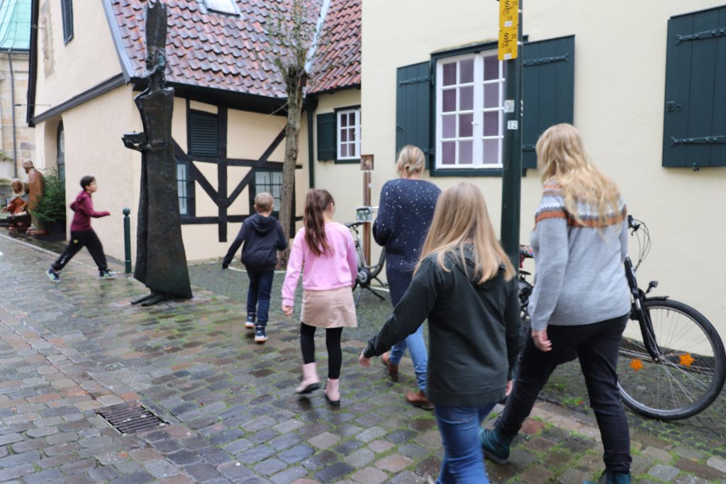 Vier Kinder und zwei erwachsene Personen gehen auf das Gebäudes des Museums zu.