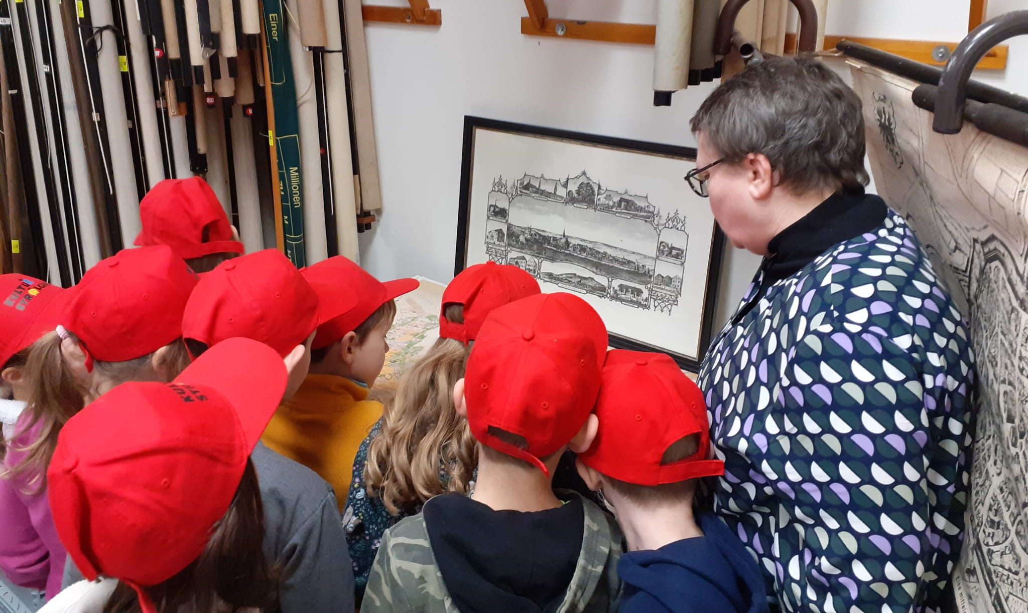 Kinder mit roten Kappen betrachten ein Bild.